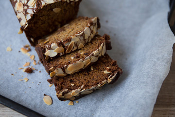 A baked banana bread on an oven plate, with sliced almonds on top.