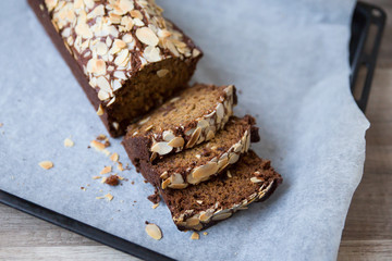 A baked banana bread on an oven plate, with sliced almonds on top.
