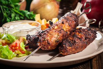 Grilled shish kebab served with fried chips and salad