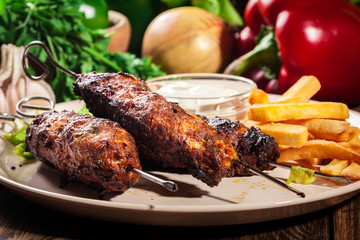 Grilled shish kebab served with fried chips and salad