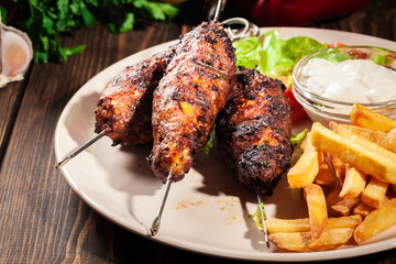 Grilled shish kebab served with fried chips and salad