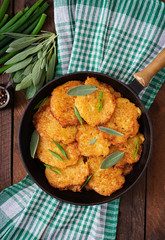 Fried potato pancakes in a frying pan on a wooden table. Top view