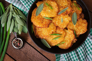 Fried potato pancakes in a frying pan on a wooden table. Top view
