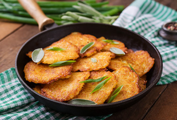 Fried potato pancakes in a frying pan on a wooden table