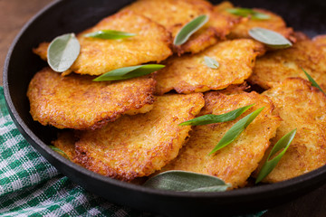 Fried potato pancakes in a frying pan on a wooden table