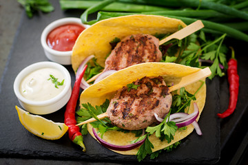Tortillas tacos with appetizing kebab (meatballs) and sauce on black background