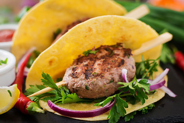 Tortillas tacos with appetizing kebab (meatballs) and sauce on black background