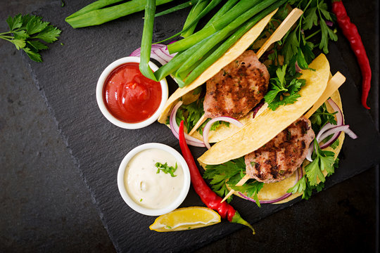 Tortillas tacos with appetizing kebab (meatballs) and sauce on black background. Top view