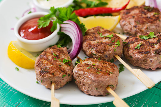 Appetizing kofta kebab (meatballs) with sauce and tortillas tacos on a white plate