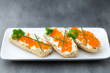Red caviar on bread on white plate.