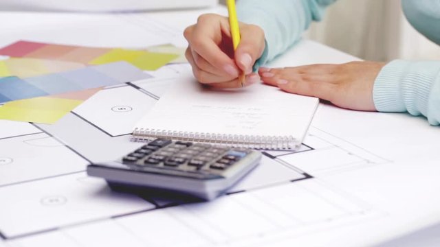 woman with blueprint counting on calculator
