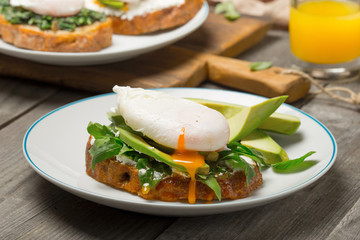 Poached egg on piece of bread with avocado and arugula