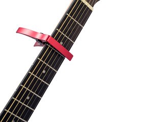 Red capo on guitar fingerboard, white background , close up
