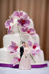Fototapeta na wymiar Beautifully decorated wedding cake with figurines of the bride and groom 