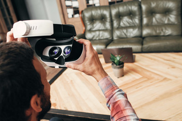 Back view of man wearing virtual reality glasses. Guy preparing to enjoy innovational gadget - vr glasses test. Modern technology, innovation, cyberspace, entertainment concept