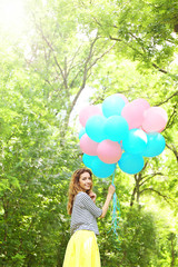 Beautiful young woman with colorful balloons in park