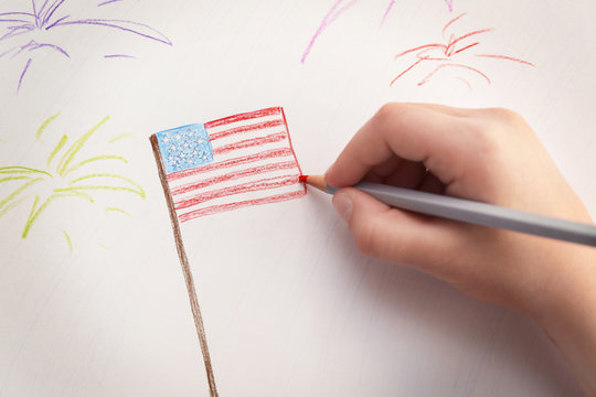 Child's hand drawing American flag on paper