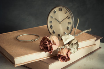 still life photography : clock with dry rose, old book and bangle in nostalgia concept ( vintage...