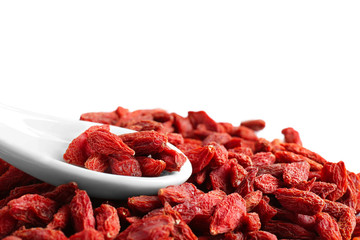 Heap of dried goji berries with spoon on white background