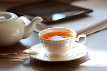 Cup of tea with tablet on table