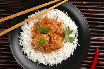 Tasty dinner with chicken curry and rice in plate on bamboo background
