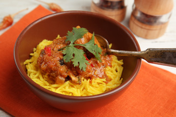 Tasty dinner with chicken curry and rice in bowl on napkin