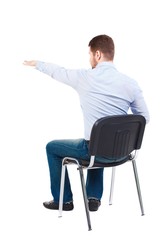 back view of young business man sitting on chair and pointing. Bearded businessman sitting on a chair and shows his hand forward.