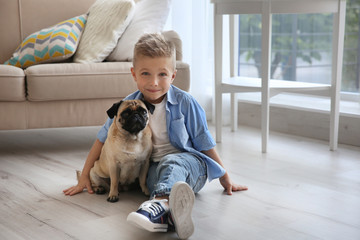 Cute boy with pug dog on floor