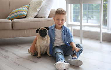 Cute boy with pug dog on floor