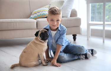 Cute boy with pug dog on floor
