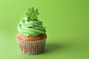 Tasty cupcake with clover on green background. Saint Patrics Day concept