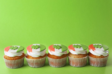 Tasty cupcakes with clover on green background. Saint Patrics Day concept
