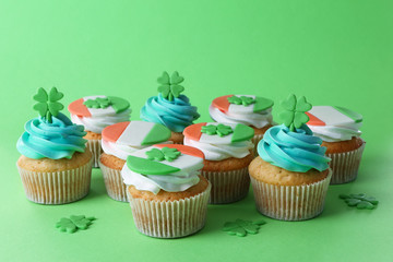 Tasty cupcakes with clover on green background. Saint Patrics Day concept