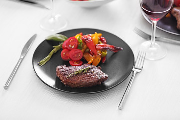 Tasty steak with fried vegetables on dinner table