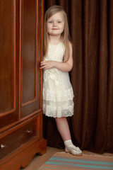 The girl peeks out from behind the wardrobe