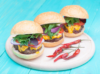 hamburgers pepper cheese onions sauce tomatoes on paper