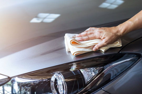 woman cleaning metalic gray color car with microfiber cloth at home on weekend