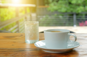 White coffee and glass water on wooden table.blurred green backg