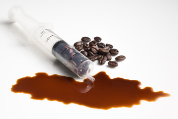Still life photography : caffeine addiction concept in coffee beans in syringe with coffee drink spilled on the floor