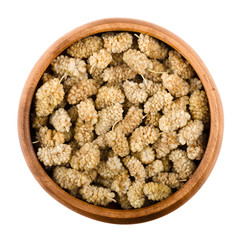 White mulberries in a wooden bowl on white background. Ocher dried edible fruits of Morus alba, widely used in pies, tarts, wines, cordials and tisanes. Isolated macro food photo close up from above.