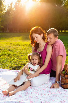 Happy young family having picnic at meadow
