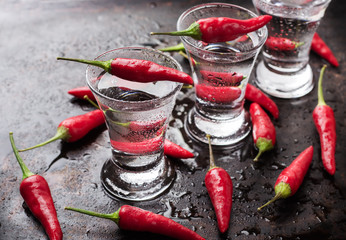 Vodka with chili peppers on rusty grunge table