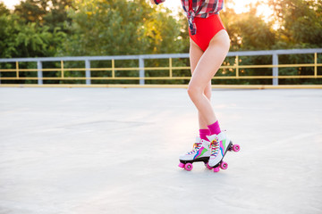 Legs of woman in swimsuit skating on roller skates outdoors