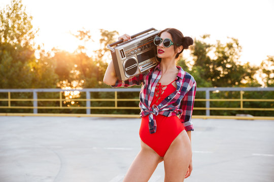 Woman standing outdoors and holding old vintage boombox