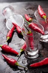 Vodka shot with chili peppers on rusty grunge table