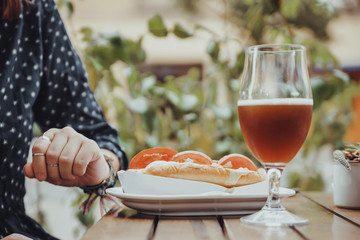 A Person Drinking Beer And Eating A Hotdog