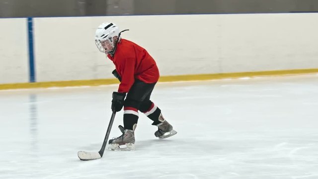 Slow motion tracking of novice ice hockey player dribbling puck and failing to score goal as little forward from opposing team sweep checking him