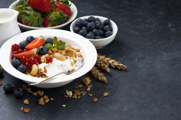 Baked muesli with fresh berries and yogurt on a dark background
