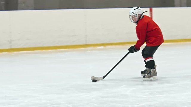 Slow motion tracking of novice ice hockey forward tricking opposite teams player and scoring goal