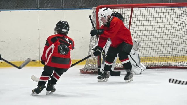 Lockdown shot of little ice hockey defenseman helping novice goalie protect teams net and saving goal
